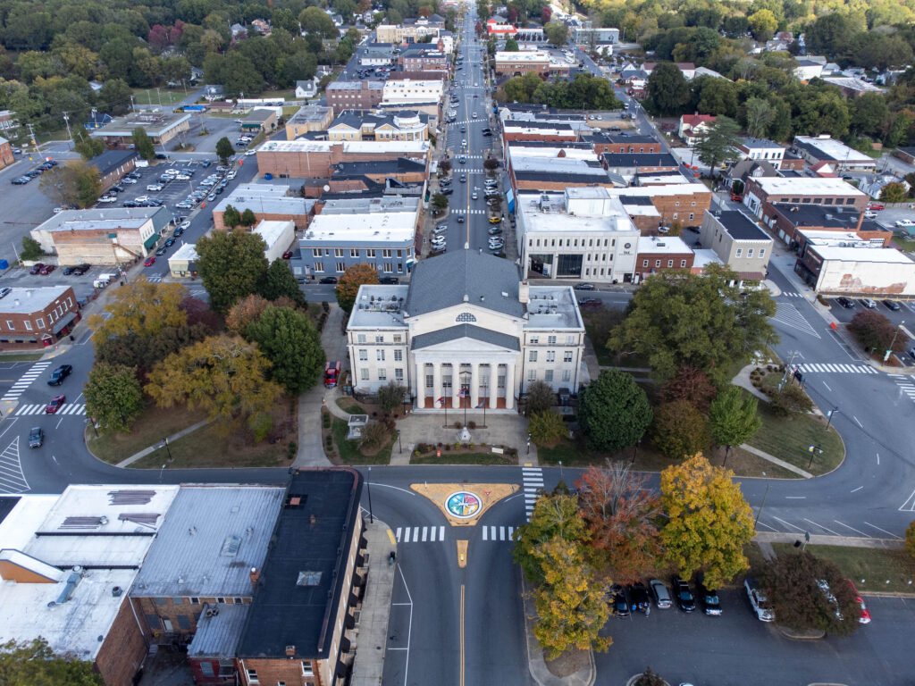 Aerial view of a small city downtown with a large courthouse, surrounding buildings, streets, and trees in autumn.