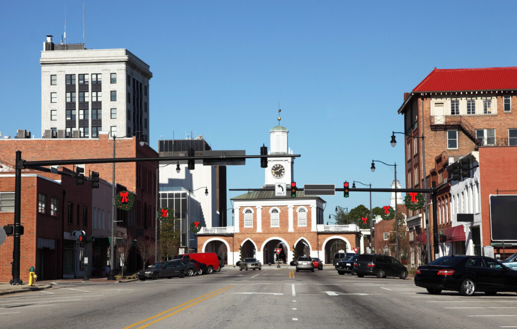 A downtown street view with traffic lights, brick buildings, and a clock tower on a clear day.