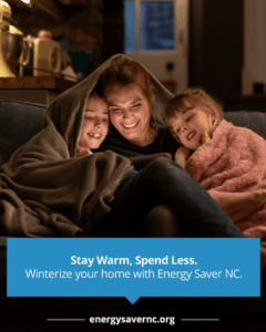 A woman sitting on a couch with two children, all wrapped in blankets, smiling and looking at a tablet together.